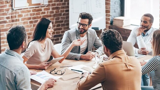 Junge Menschen sitzen lachend in einem Teammeeting