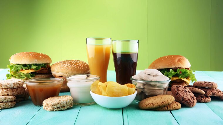 Abbildung von verschiedenen hochverarbeiteten Lebensmitteln: Fast Food, Softdrinks, Saucen und Süßigkeiten