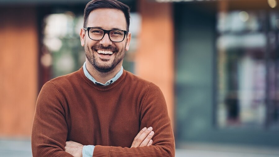 lachender junger Mann mit verschränkten Armen
