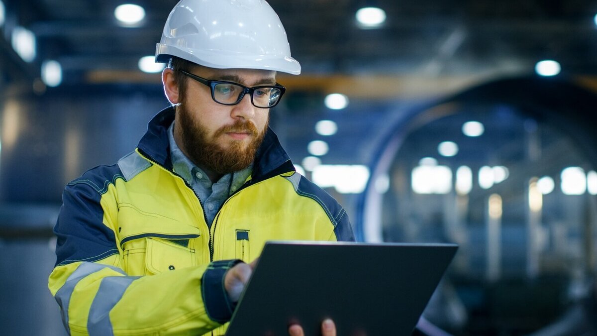 Arbeitsschutz Arbeiter mit Helm sieht sich Arbeitsschutz Online-Impulsvortrag bei seiner Arbeit auf dem Tablet an