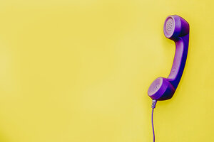 Lila farbendes Telefon vor gelbem Hintergrund
